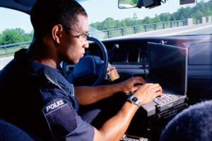 Police officer doing a training in his cruiser on a laptop