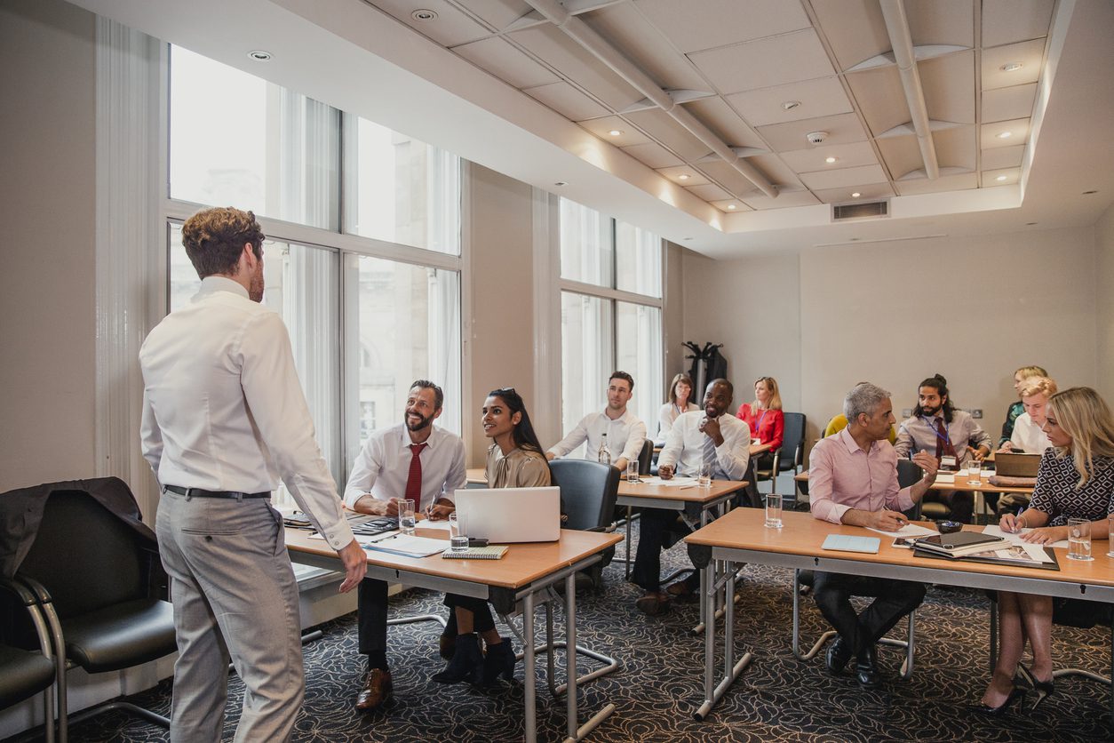 Rear view of an businessman giving a presentation at a conference.