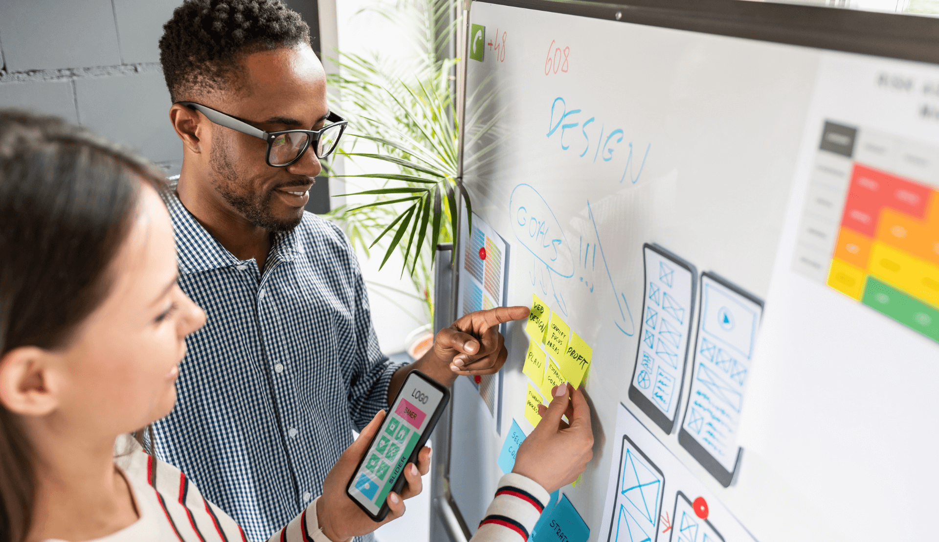 two people looking at a whiteboard with accessibility factors for a website mapped out on it.