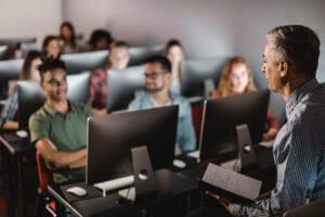 Mid adult male teacher teaching the lecture in computer lab