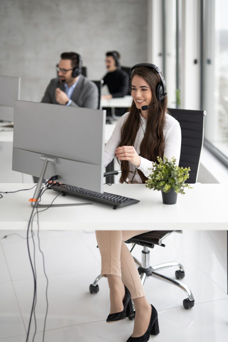 Vertical view of happy call center agent woman working on support hotline in office.