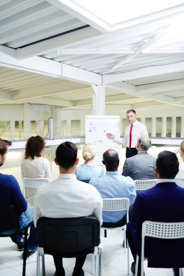Professional economist pointing at paper on whiteboard while making report for audience